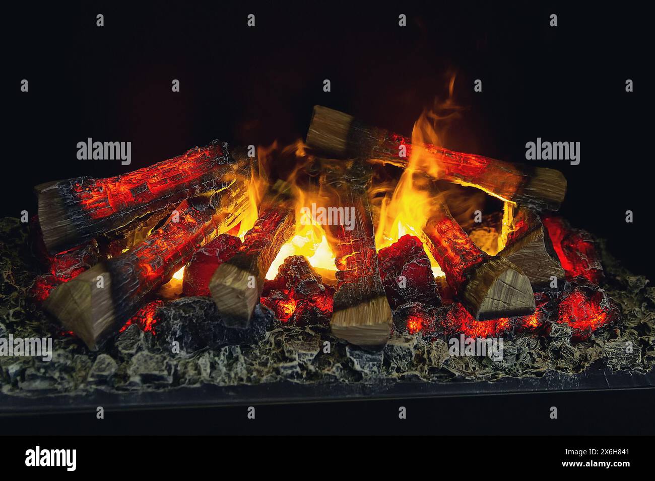 Les bûches de la cheminée brûlent avec un feu vif. Cheminée décorative artificielle avec imitation du feu. Banque D'Images