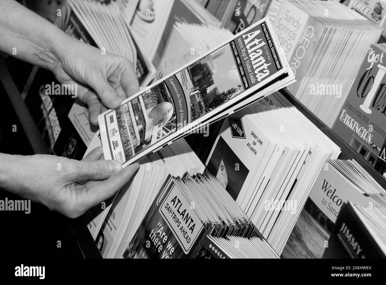 Femme caucasienne tenant une brochure de voyage d'Atlanta, Géorgie prise d'un rack. ÉTATS-UNIS. Banque D'Images