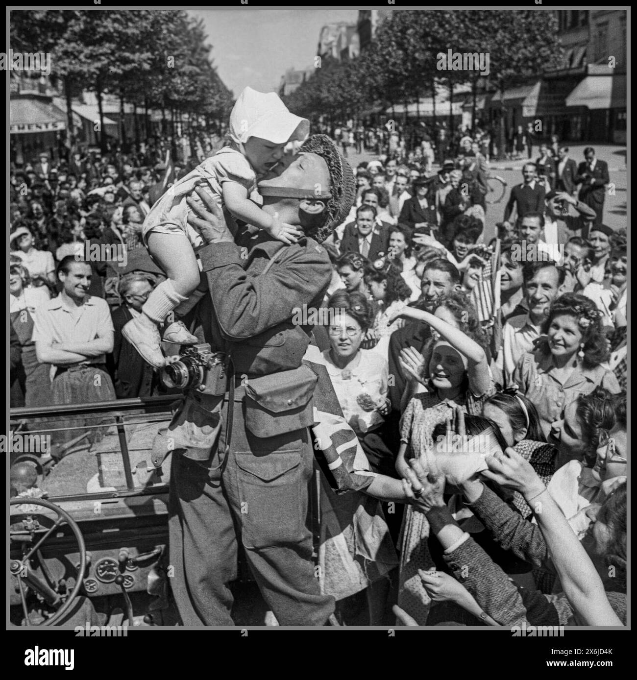 1944 Paris WW2 libération août 1944 Un photographe de l'armée britannique embrasse un bébé entouré de foules parisiennes extatiques Paris France Banque D'Images