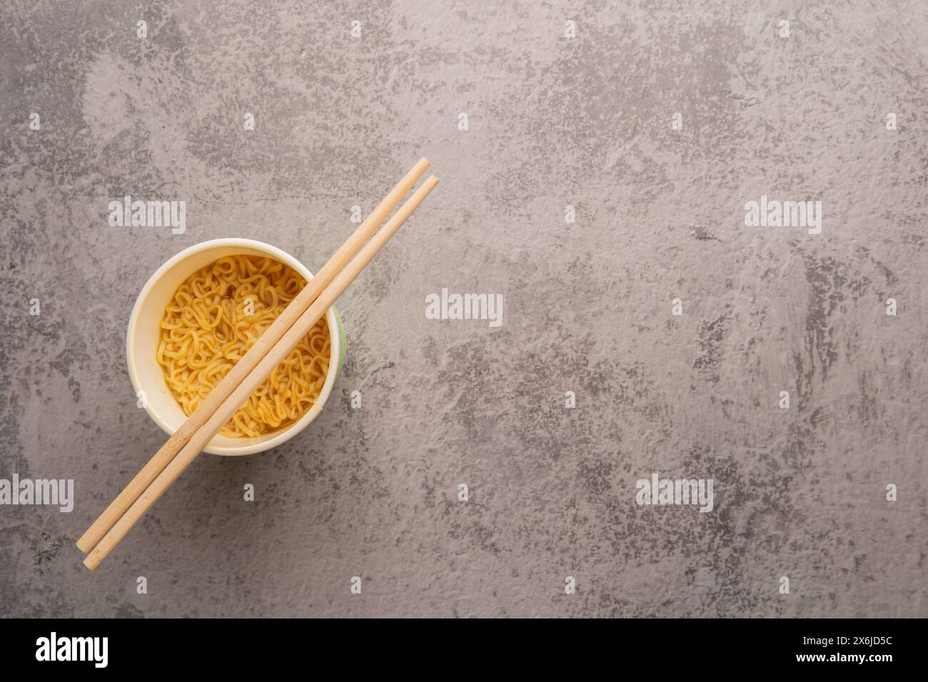 Aperçu d'un bol de soupe de pâtes instantanées avec une paire de chopstickson un fond gris clair. Déjeuner. Concept de restauration rapide Banque D'Images