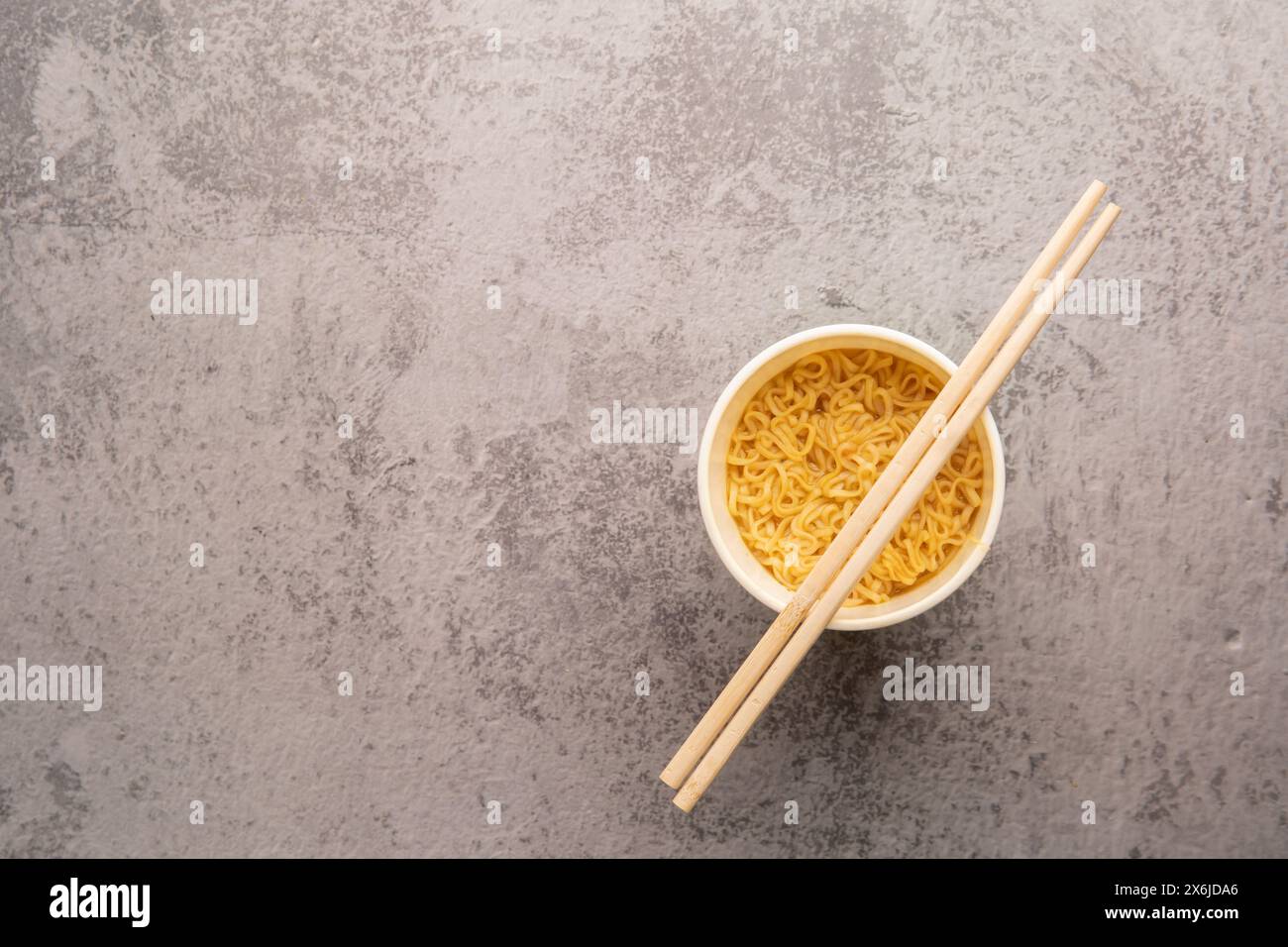 Aperçu d'un bol de soupe de pâtes instantanées avec une paire de chopstickson un fond gris clair. Déjeuner. Concept de restauration rapide Banque D'Images