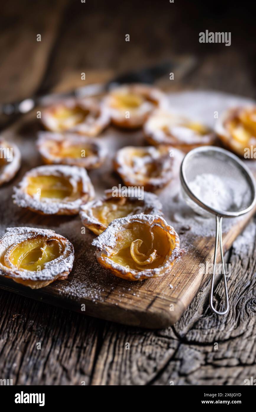 Mini tartes faites de pâte feuilletée et de pommes tranchées saupoudrées de sucre en poudre Banque D'Images