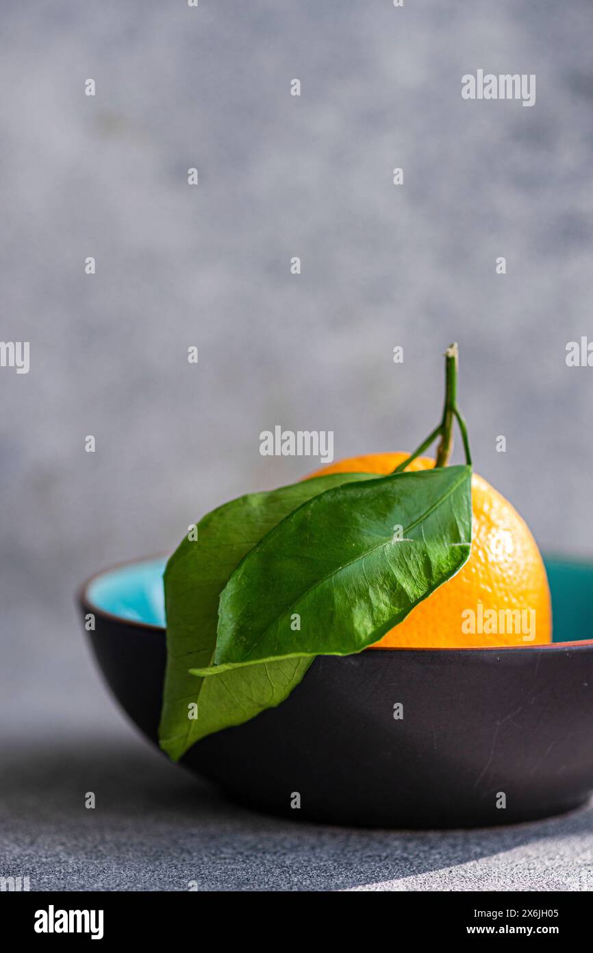 Orange avec des feuilles dans un bol en céramique Banque D'Images