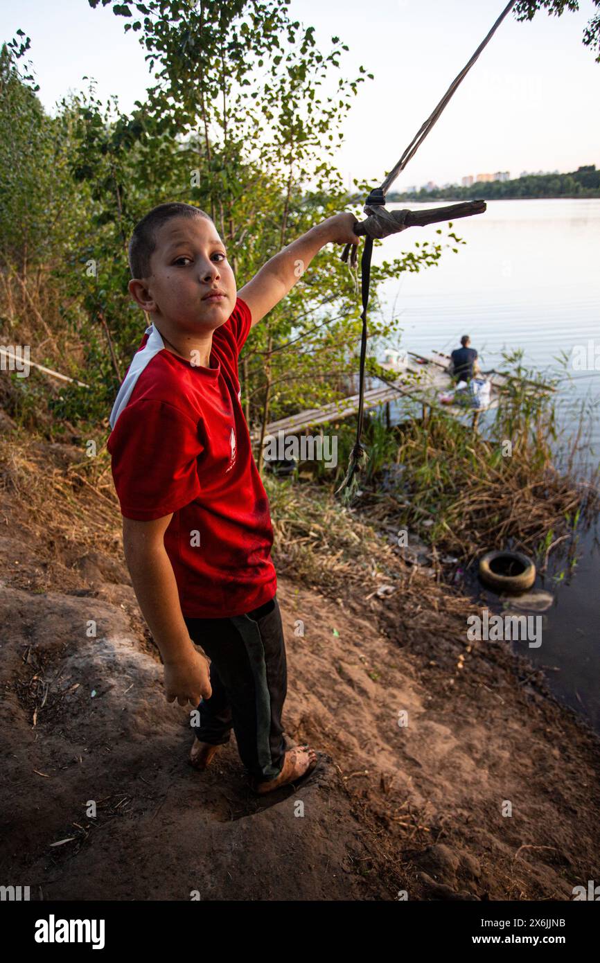 Le jeune garçon se prépare à sauter un élastique en bois primitif auto-fabriqué (Tarzanka) sur le rivage en Ukraine, une attraction populaire de saut d'eau. Banque D'Images