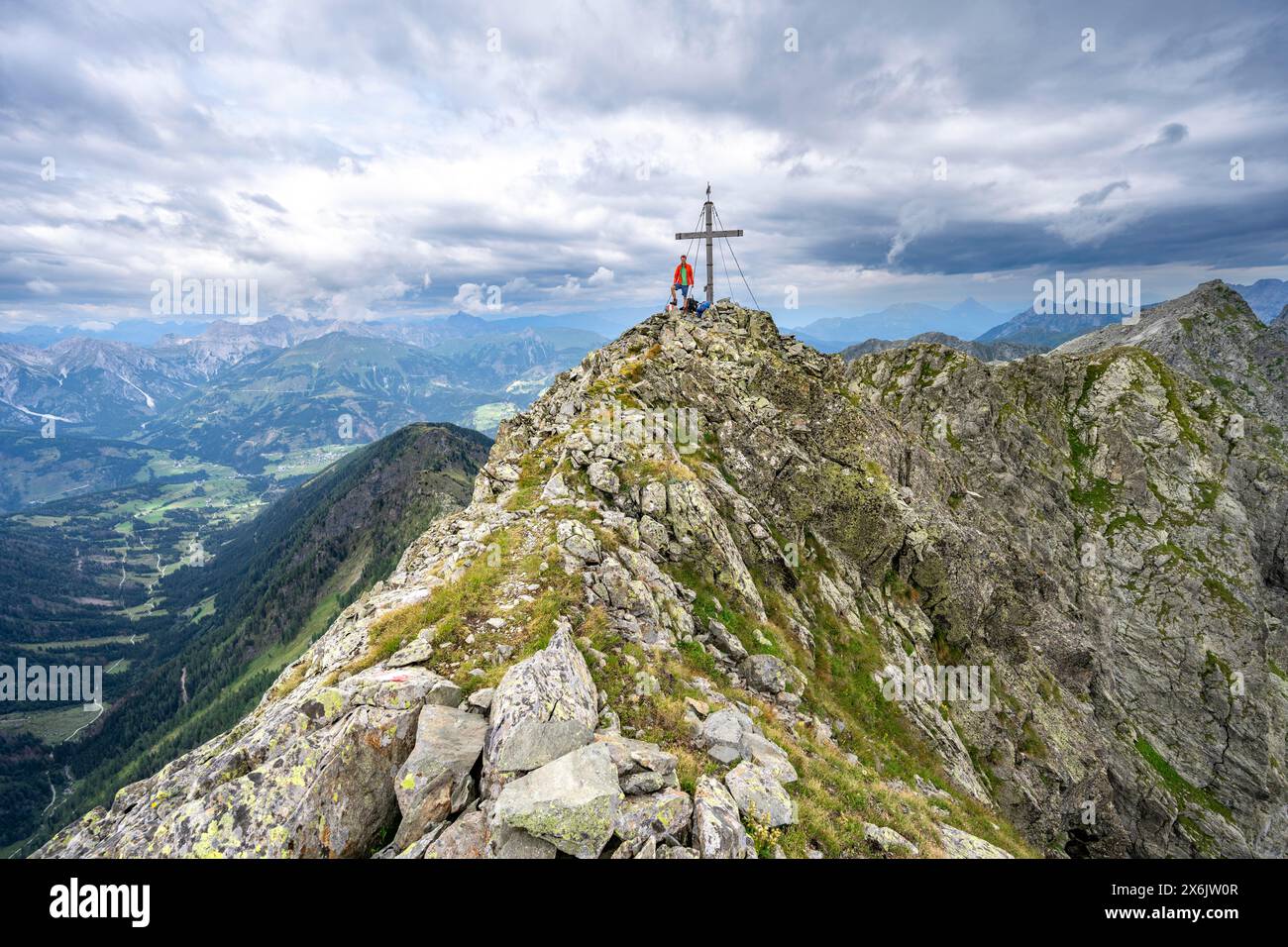 Alpiniste sur le sommet pointu rocheux de la Raudenspitze ou Monte Fleons avec sommet cross, panorama de montagne sur la crête principale de Carnic, Carnic Banque D'Images