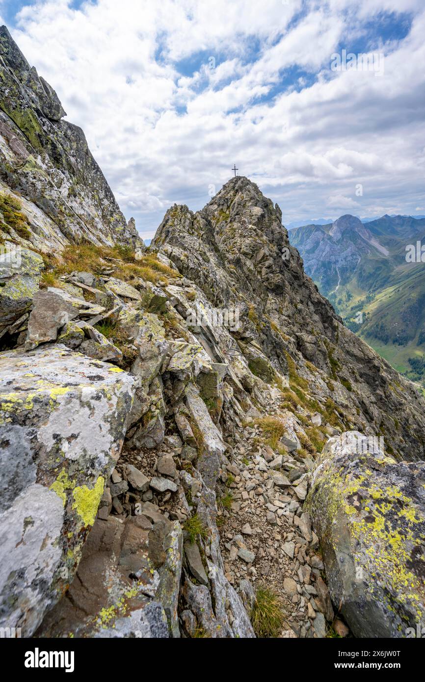 Sentier de montagne étroit, sommet rocheux de la Raudenspitze ou Monte Fleons, avec croix sommitale, Carnic main Ridge, Carnic Alps, Carinthie, Autriche Banque D'Images