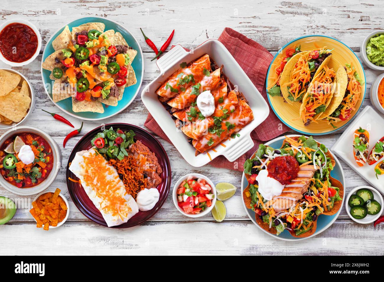 Scène de table de nourriture mexicaine. Vue de dessus sur un fond de bois blanc. Tacos, assiette burrito, nachos, enchiladas, soupe de tortilla et salade. Banque D'Images
