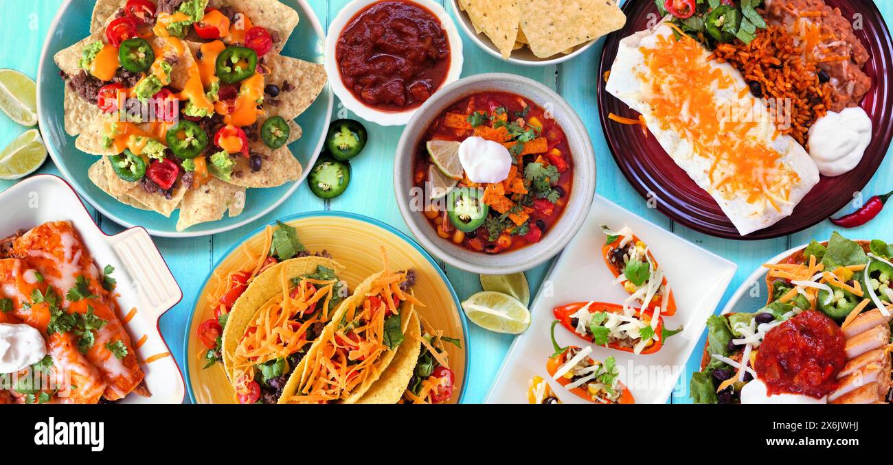 Scène de table de nourriture mexicaine. Vue au-dessus sur un fond de bannière en bois bleu. Tacos, assiette burrito, nachos, enchiladas, soupe de tortilla et salade. Copier l'espace. Banque D'Images