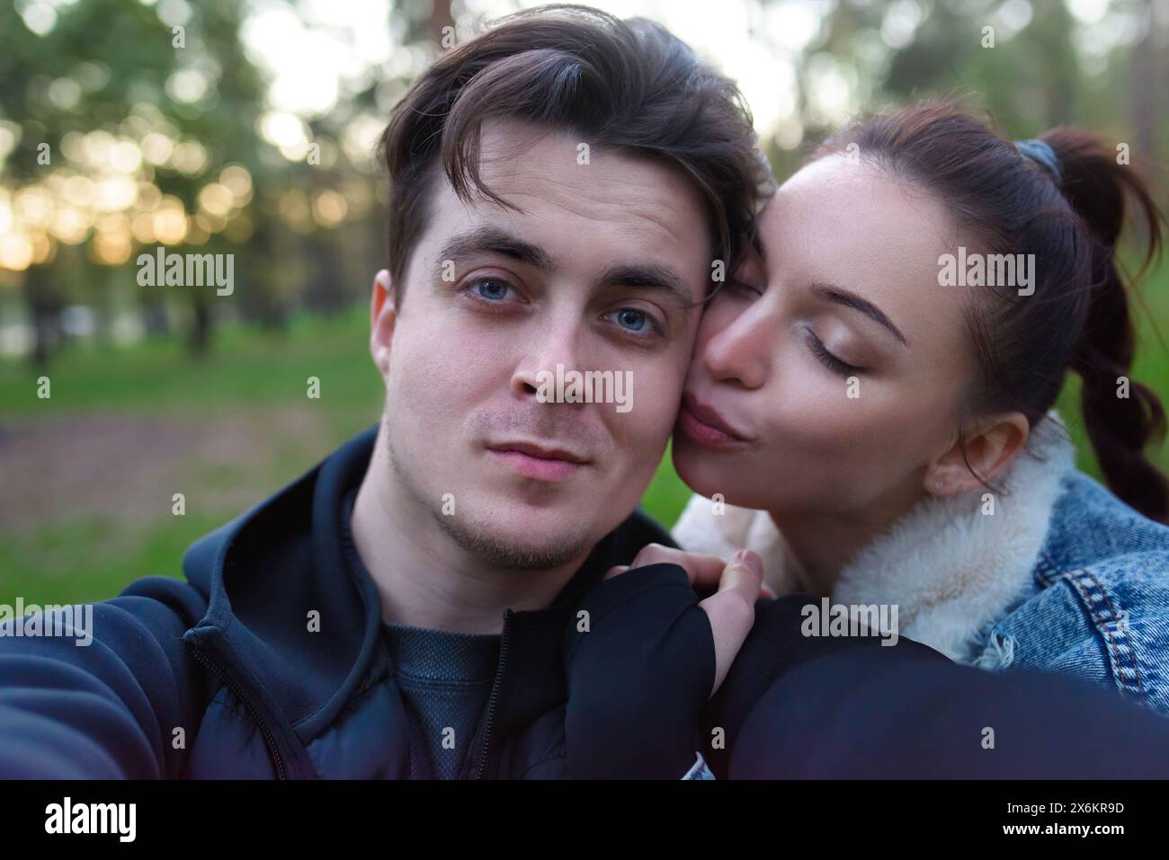 Selfies dans la nature d'un couple aimant homme et femme. La femme embrasse l'homme sur la joue. ensemble Banque D'Images