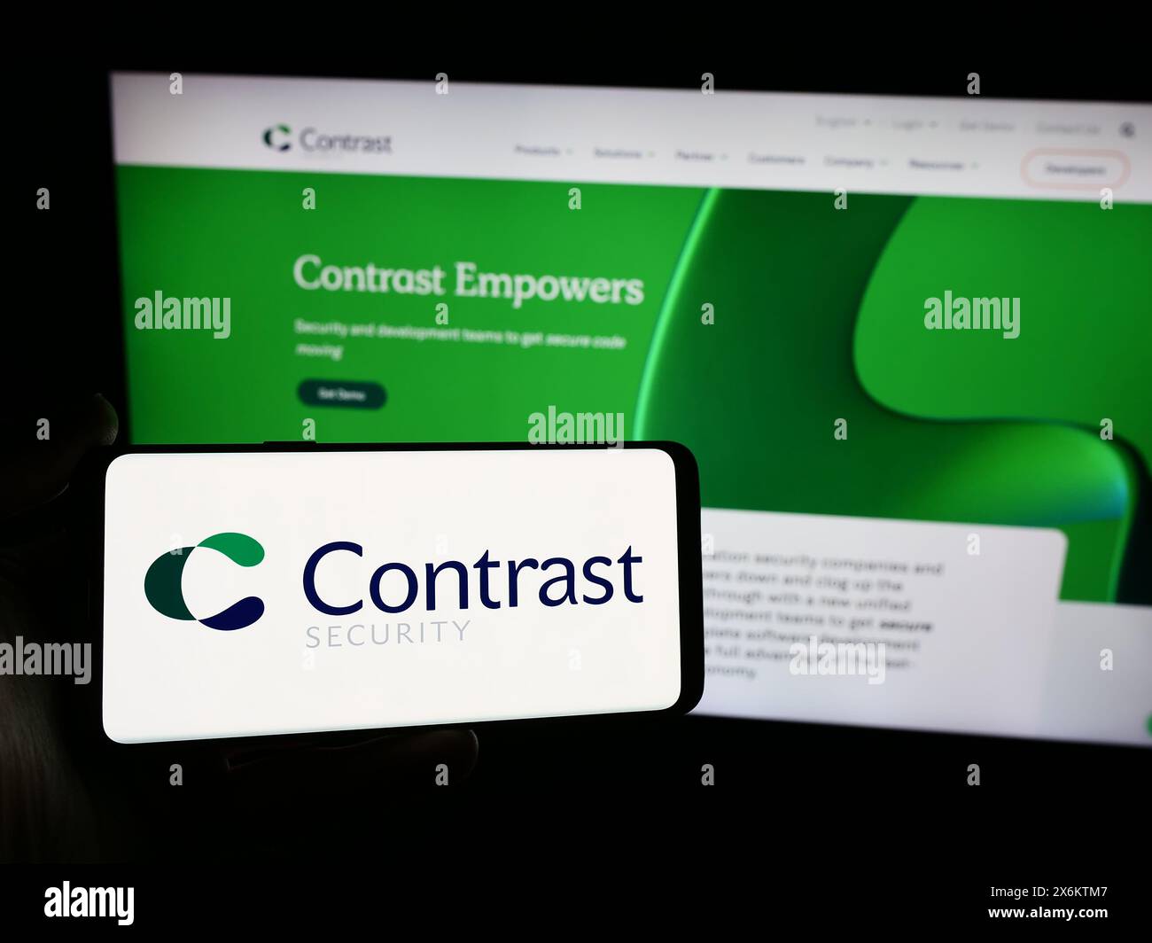 Personne tenant un smartphone avec le logo de la société de logiciels américaine Contrast Security Inc devant le site Web. Concentrez-vous sur l'affichage du téléphone. Banque D'Images