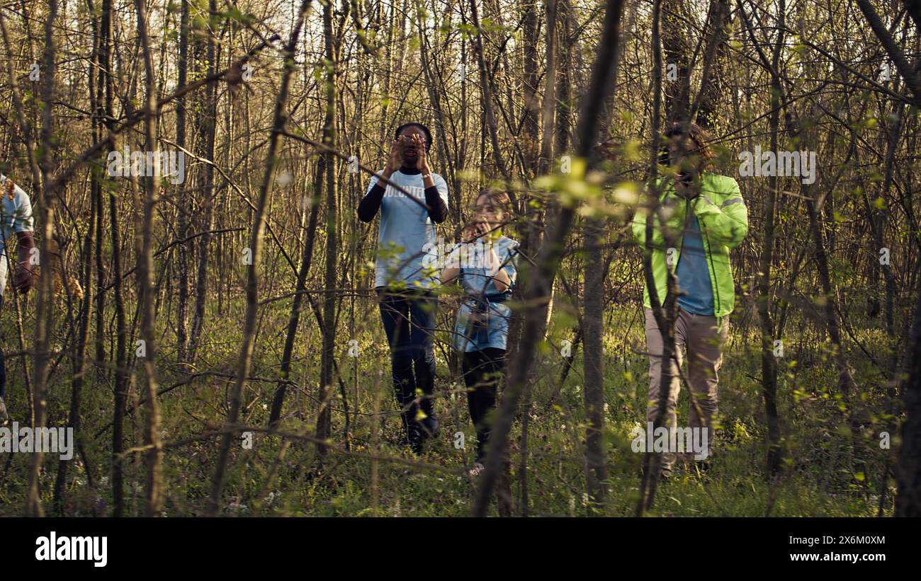 Groupe de sauveteurs bénévoles à la recherche d'une personne disparue, appelant leur nom dans les bois et traversant les arbres pour suivre les étapes. Recherchez les sauveteurs de l'escouade à la recherche d'une victime perdue. Caméra B. Banque D'Images