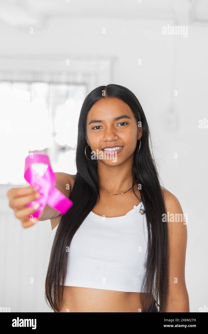jeune femme brune latine tenant dans sa main un ruban rose symbole de la lutte contre le cancer du sein Banque D'Images