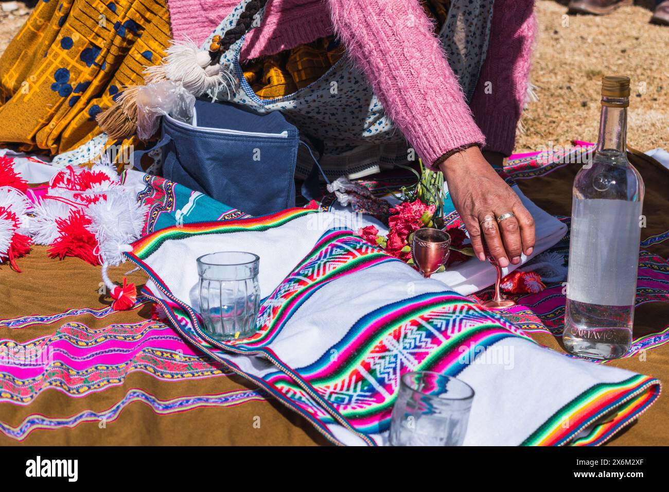 Rituel traditionnel de paiement à la terre avec des feuilles de coca et chicha de jora dans les Andes de la chaîne de montagnes par une journée ensoleillée Banque D'Images