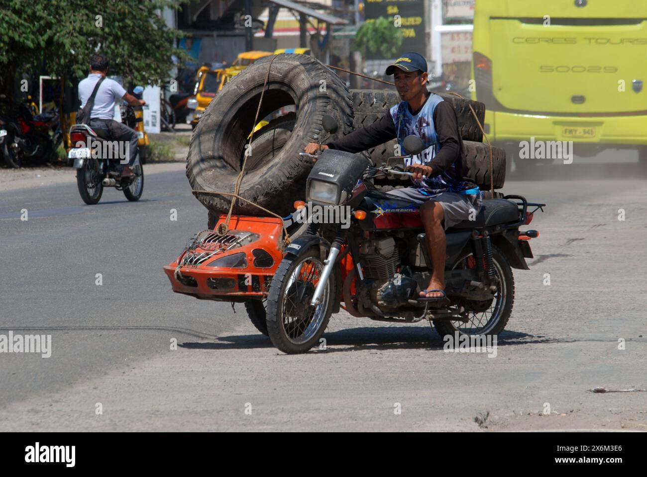 Homme sur moto portant de gros pneus, Cadix City, Negros Occidental, Philippines. Banque D'Images