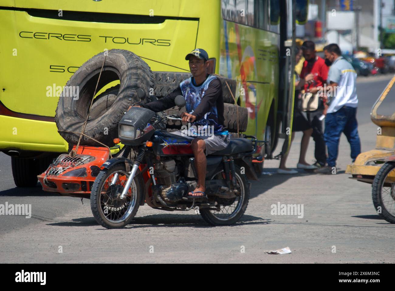 Homme sur moto portant de gros pneus, Cadix City, Negros Occidental, Philippines. Banque D'Images