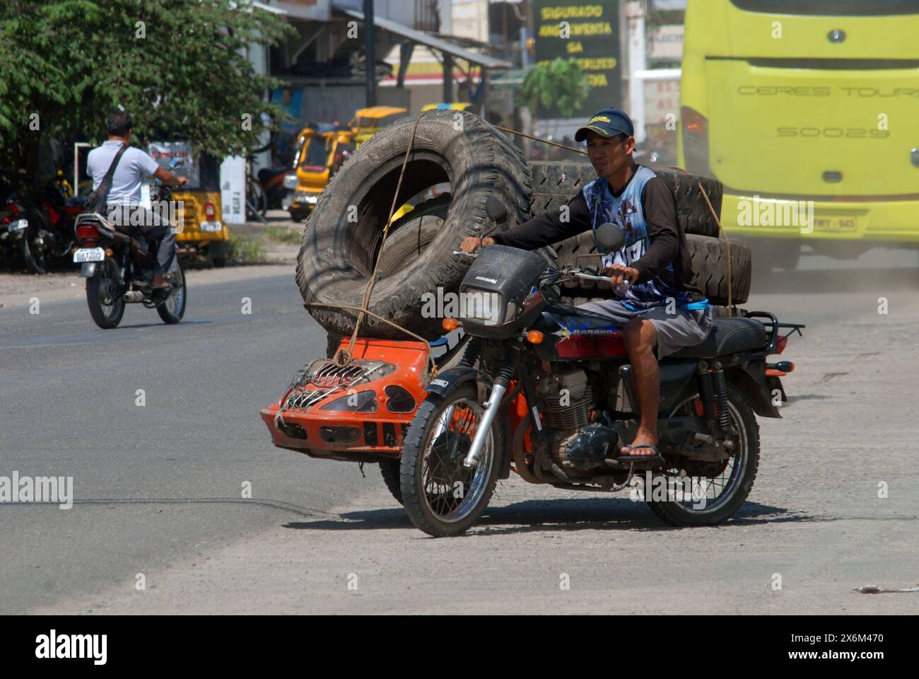 Homme sur moto portant de gros pneus, Cadix City, Negros Occidental, Philippines. Banque D'Images