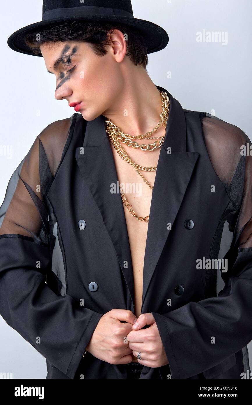 Adorable gay caucasien impressionnant en vêtements noirs posant regardant vers le bas, avec un maquillage de fête lumineux sur le visage. attrayant beau calme calme modèle masculin iso Banque D'Images