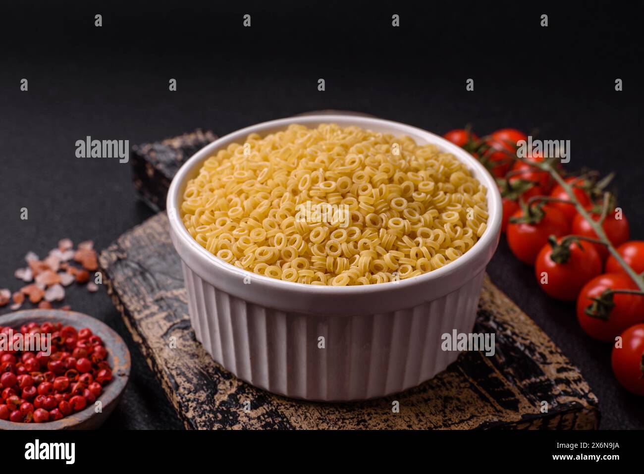 Pâtes anellini crues de blé dur avec du sel et des épices sur un fond de béton foncé Banque D'Images