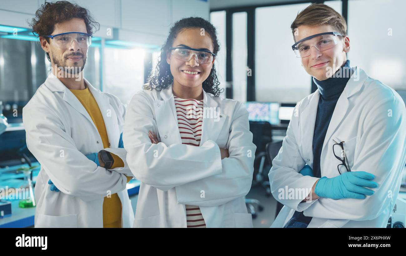 Laboratoire des sciences médicales avec une équipe de trois jeunes scientifiques à succès. Belle femme noire, beau latin et homme caucasien scientifiques sourient en regardant Camera. Portrait moyen Banque D'Images