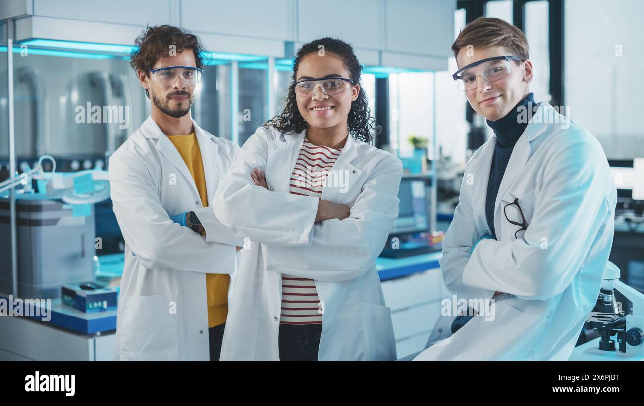 Laboratoire des sciences médicales avec une équipe de trois jeunes scientifiques à succès. Belle femme noire, beau latin et homme caucasien scientifiques sourient en regardant Camera. Portrait moyen Banque D'Images