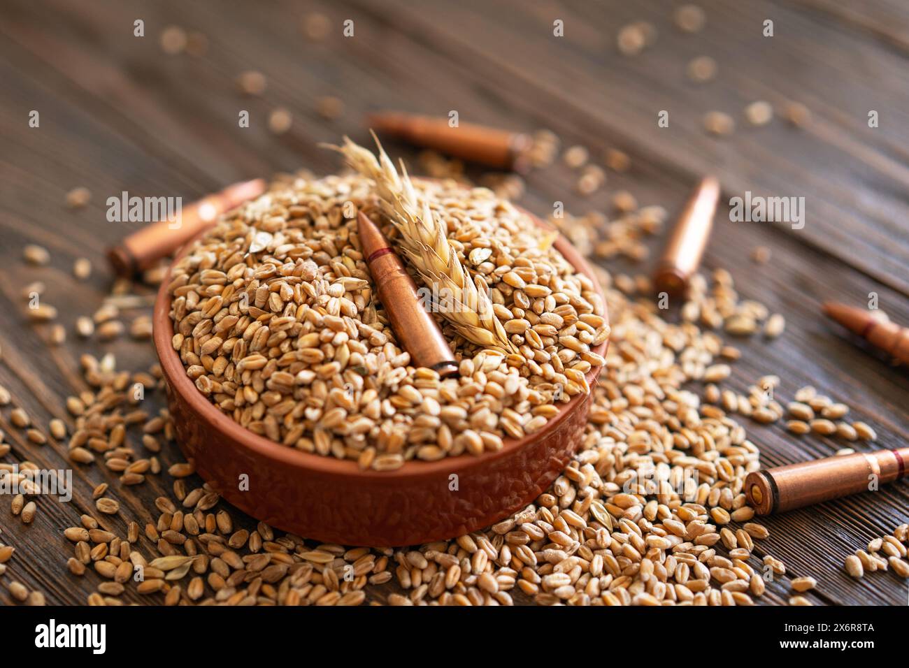 Les grains de blé sont répartis sur une table en bois, entrecoupée de plusieurs obus métalliques. Le concept de la photo suggère que le grain peut être utilisé Banque D'Images