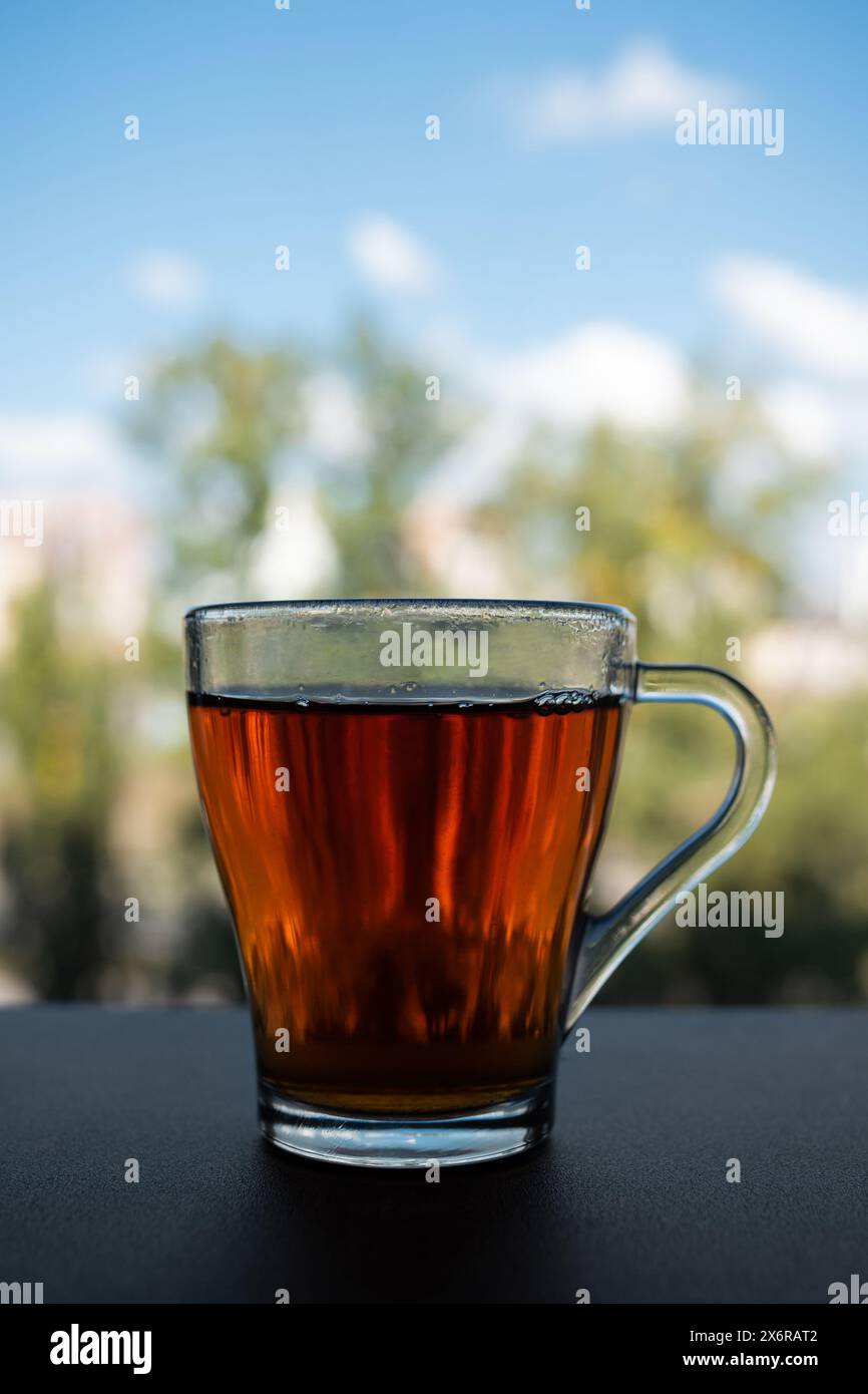 Une tasse de verre de thé parfumé se tient près de la fenêtre Banque D'Images