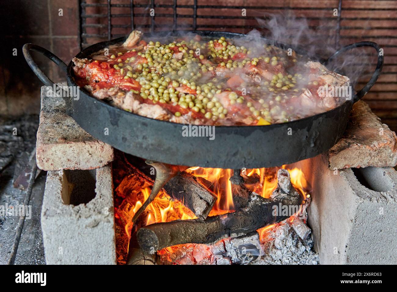 Pollo al disco cuisinant au feu de bois sur un disque de charrue reposant sur des briques dans un parrilero en Argentine. Banque D'Images