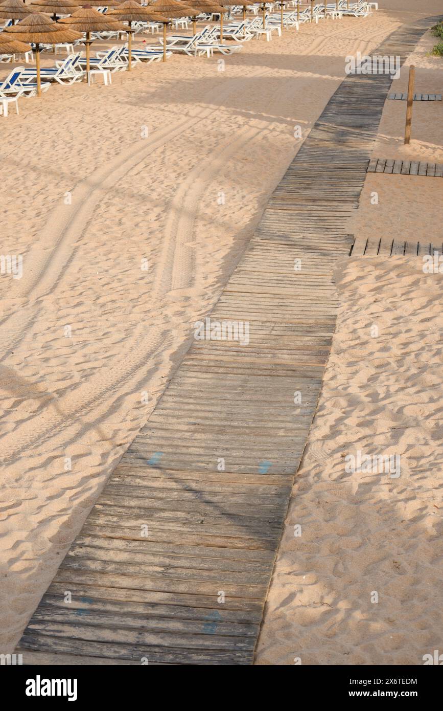 Promenade sur une plage de sable. Le parasol est d'un côté. Banque D'Images