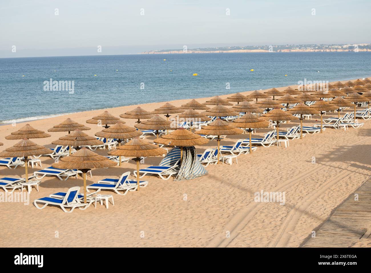 Une plage au Portugal. Praia de Galé. Algarve. Chaises longues et parasols rustiques. Banque D'Images