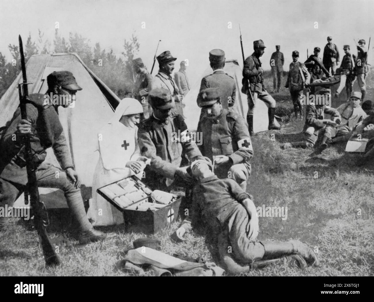 Photographie montrant une infirmière de la Croix-Rouge italienne sur le champ de bataille, soignant les blessures d'un soldat inconscient. Prise pendant la première Guerre mondiale, cette image souligne la bravoure et le dévouement du personnel médical qui a risqué sa vie pour soigner et soutenir les blessés dans le chaos de la bataille. Banque D'Images