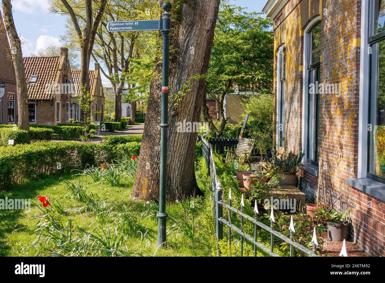 Un village idyllique avec des jardins bien entretenus, des fleurs en fleurs et un panneau de rue, des maisons historiques et une église avec de petites rues et des lanternes, Nes Banque D'Images