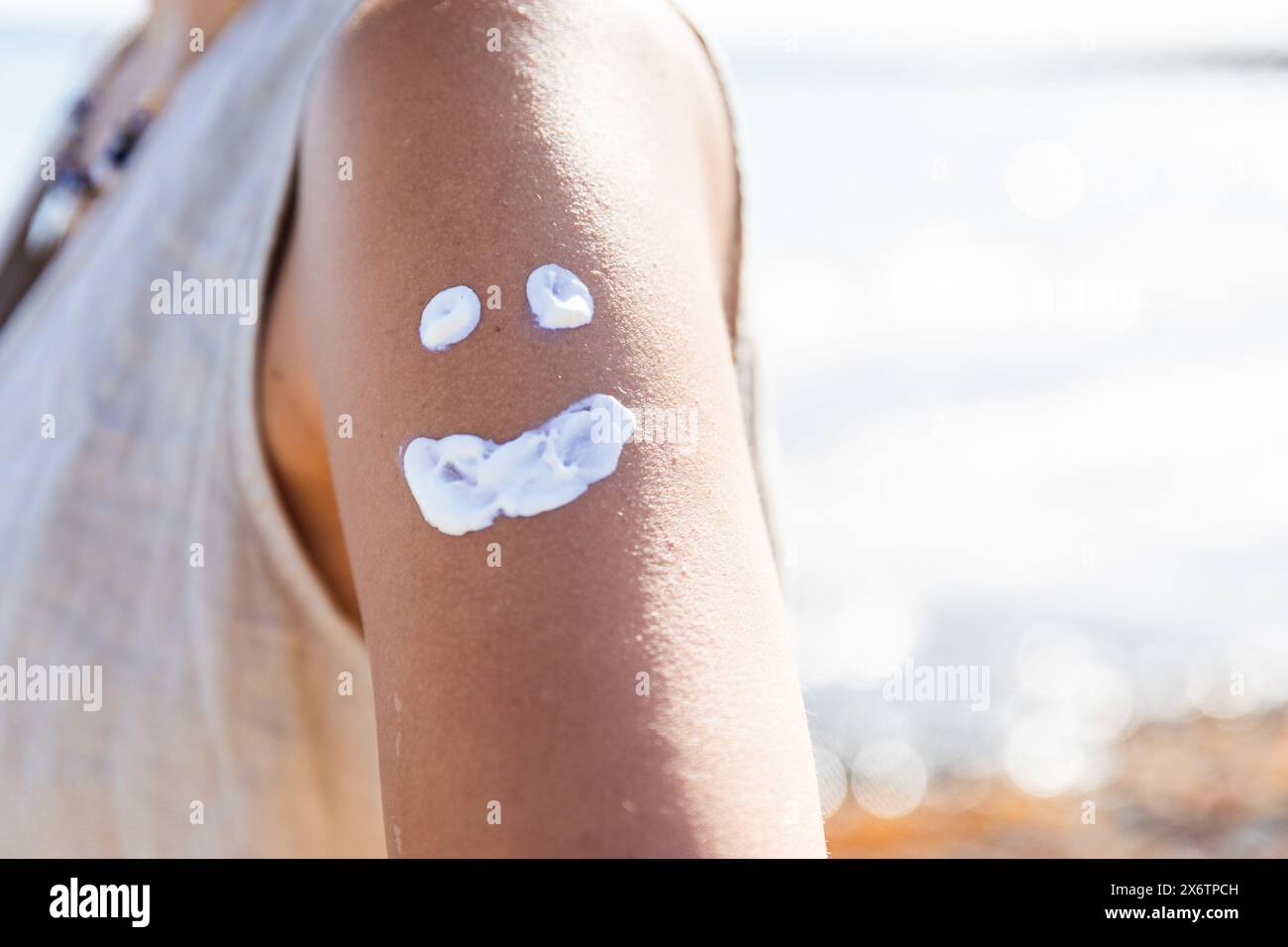 Une femme a un visage souriant dessiné sur son bras avec de la crème blanche. L'image transmet une humeur légère et ludique, suggérant que la femme a du fu Banque D'Images