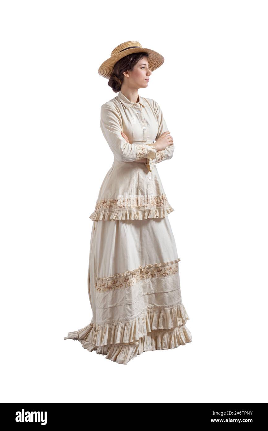 Jeune femme aux bras pliés portant une robe vintage beige des années 1880 et un chapeau de paille isolé sur blanc Banque D'Images