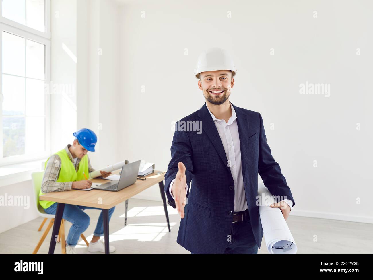 Architecte tendu la main à la caméra pour faire une affaire debout sur le chantier de construction avec contremaître Banque D'Images