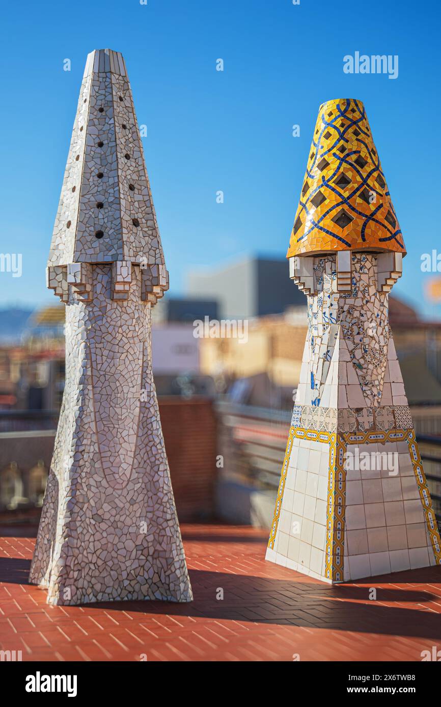 BARCELONE, ESPAGNE - 14 AVRIL 2024 : cheminées originales recouvertes de céramiques de différentes couleurs sur le toit du Palau Guell conçu par l'architecte an Banque D'Images
