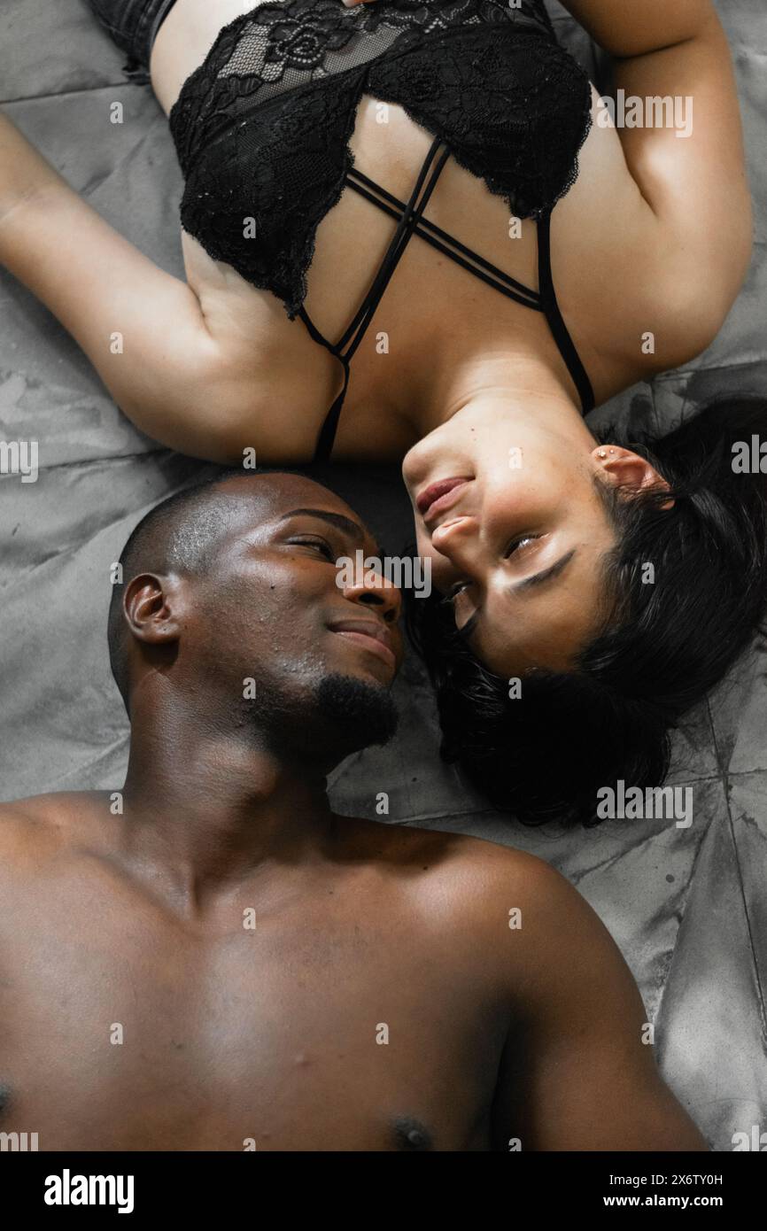 jeune couple interracial couché sur le sol se regardant dans les yeux dans une position inversée, vue zénithale Banque D'Images