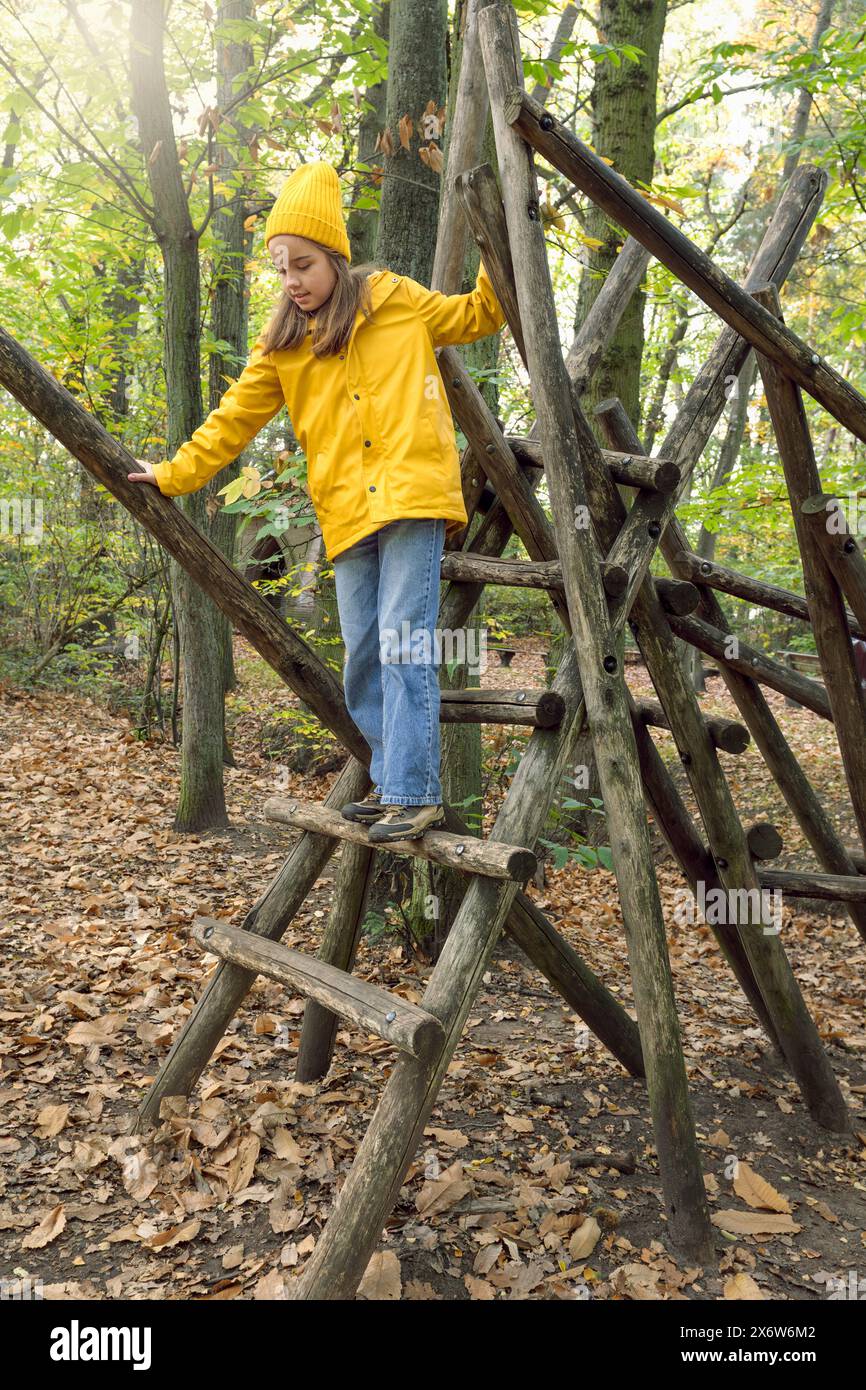 Parkour pour les enfants dans le parc. Parcours d'obstacles pour les enfants dans le parc d'automne. Une adolescente marche soigneusement sur des bûches Banque D'Images