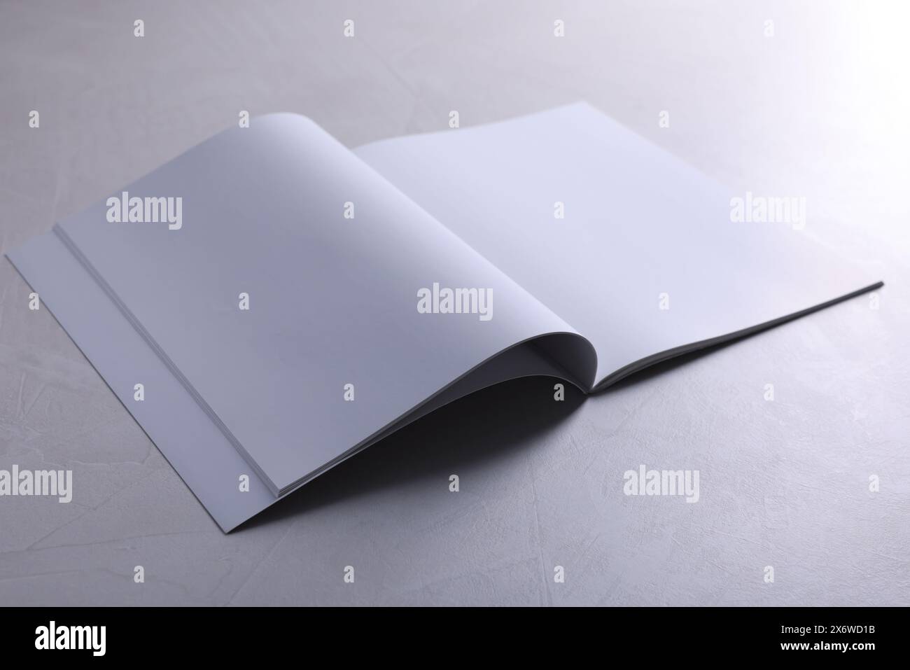Ouvrez le carnet avec des feuilles de papier vierges sur la table texturée grise. Maquette pour le design Banque D'Images