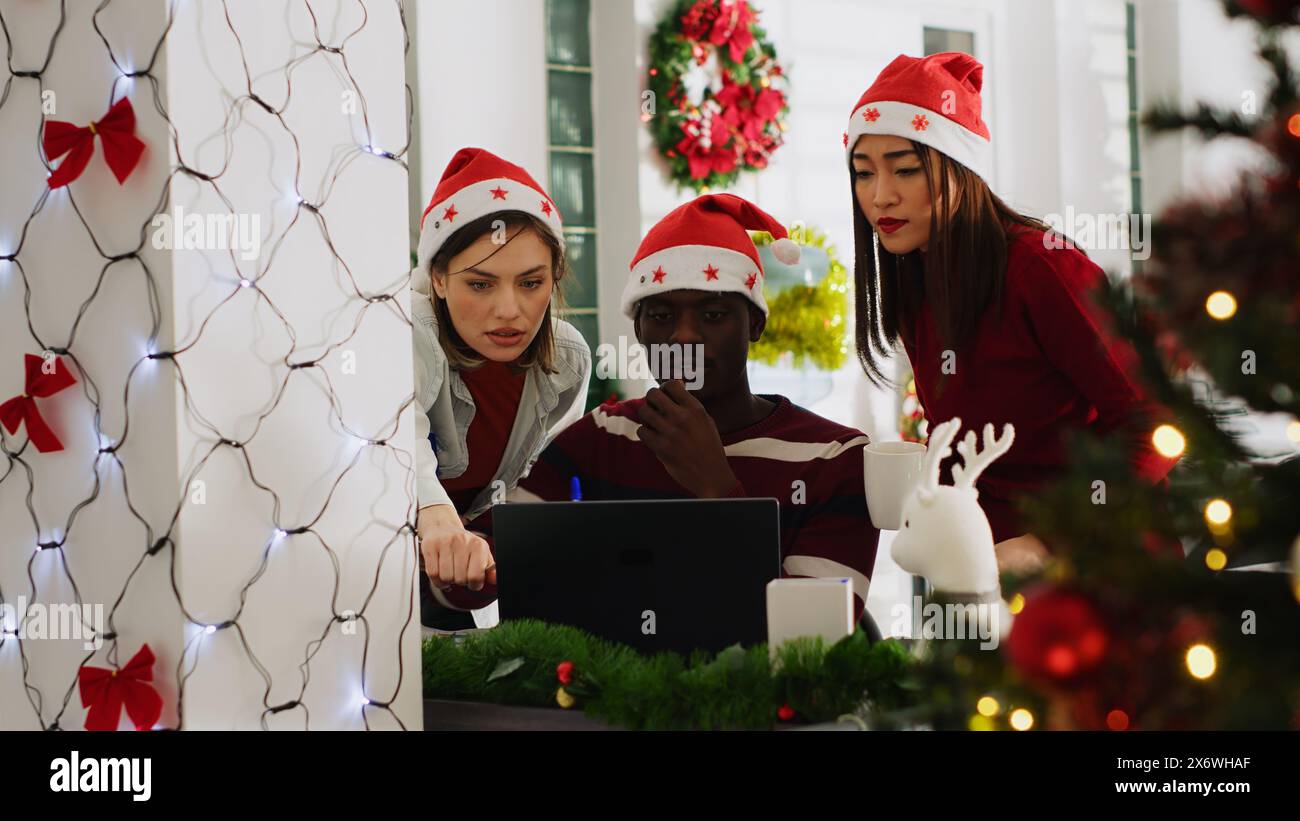 Chef d'équipe dans le bureau décoré de Noël déléguant des tâches aux membres du personnel avant la période des fêtes d'hiver. Manager enseignant au personnel de l'entreprise comment terminer correctement le projet dans l'espace de travail XMAS ADORN Banque D'Images