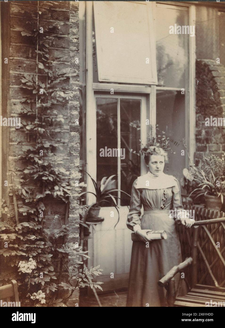 Portrait d'une jeune femme dans le jardin à la porte arrière d'une maison, photographie, anonyme, c. 1910 - c. 1920, support photographique, tirage argenté gélatineux, hauteur, 162 mm × largeur, 105 mm Banque D'Images