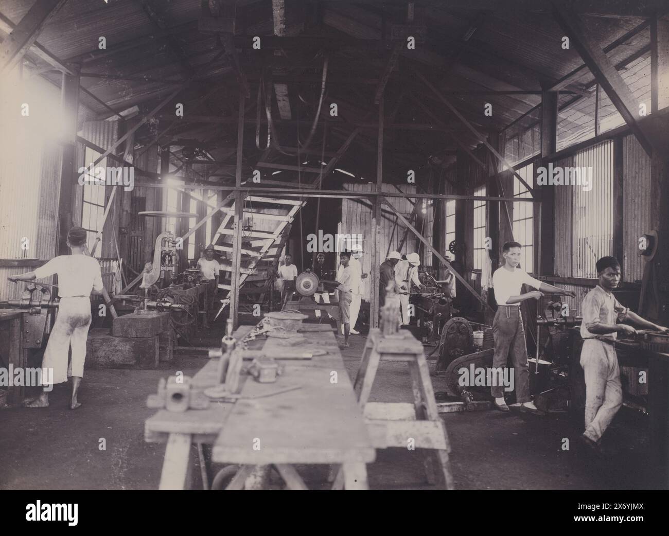 Intérieur d'atelier, vue d'un atelier avec un tour et d'autres machines. Avec un superviseur néerlandais et des travailleurs indonésiens. Partie du groupe de photos individuelles sur la construction du port de Belawan sur la côte de Medan, Sumatra 1921-1922., photographie, anonyme, Belawan, 1921 - 1922, support photographique, hauteur, 211 mm × largeur, 285 mm Banque D'Images