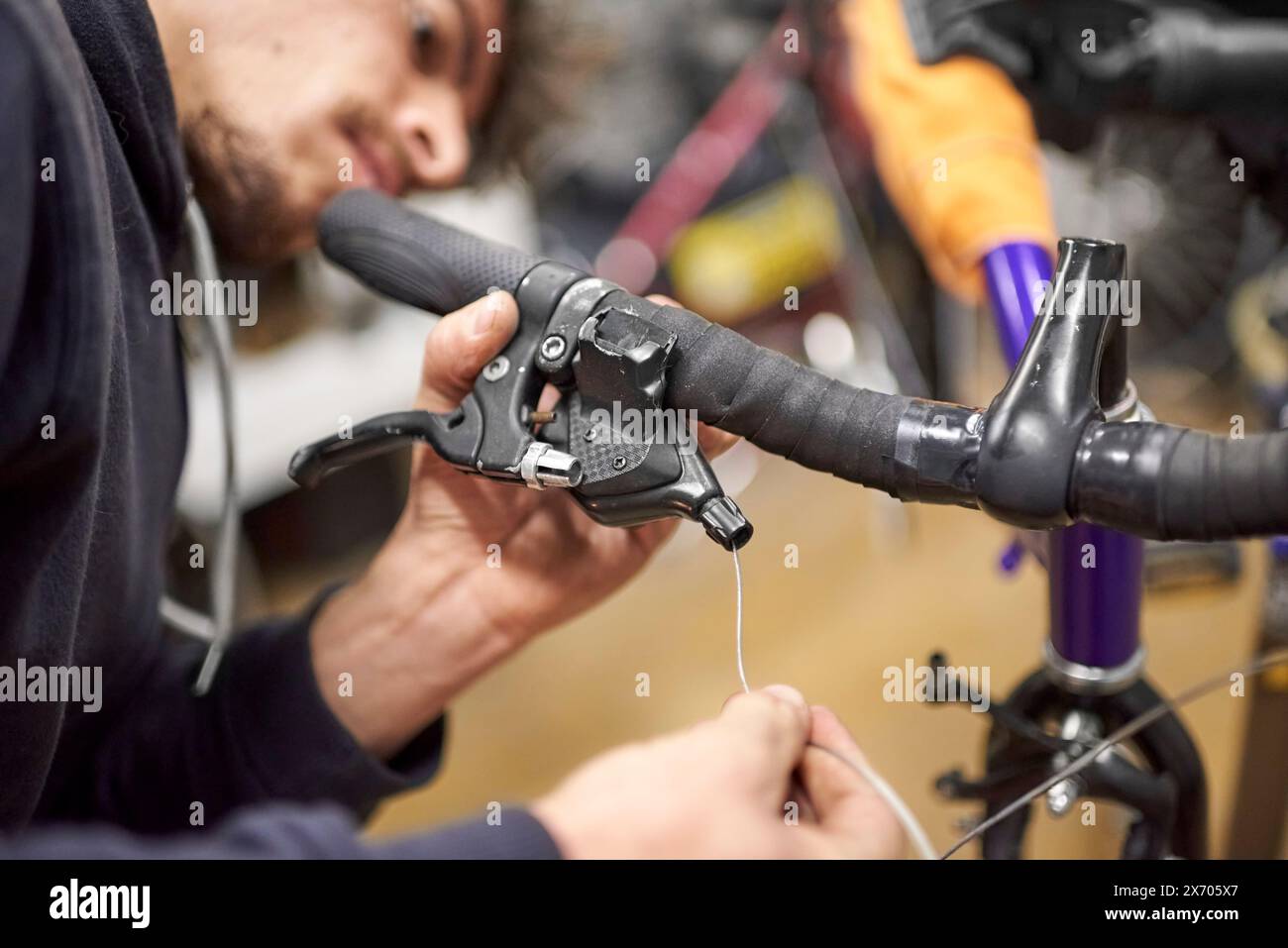 Réparateur hispanique assemblant le système de freinage d'un vélo dans le cadre du service d'entretien qu'il effectue dans son atelier. De vraies personnes au travail. Banque D'Images