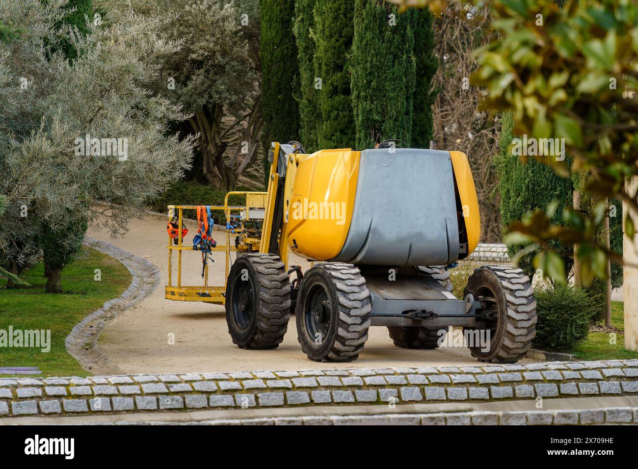 Ascenseur jaune à flèche utilisé par les ouvriers de la construction stationnés sur une passerelle dans un parc public. Madrid, Espagne. Banque D'Images