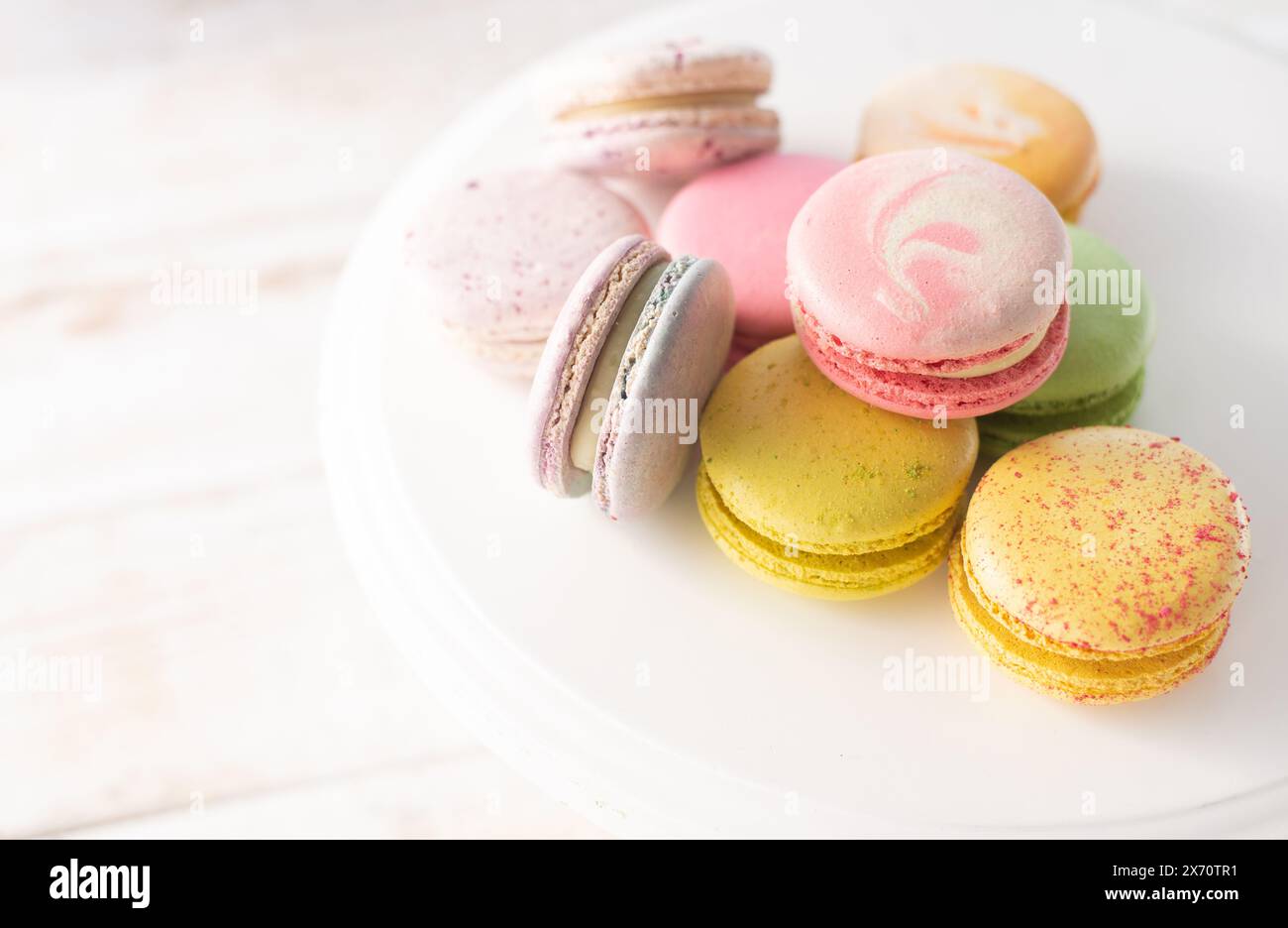 Macarons multicolores en gros plan sur fond de bois avec des lumières douces. Dessert français délicat pour le petit déjeuner à la lumière du matin. Banque D'Images