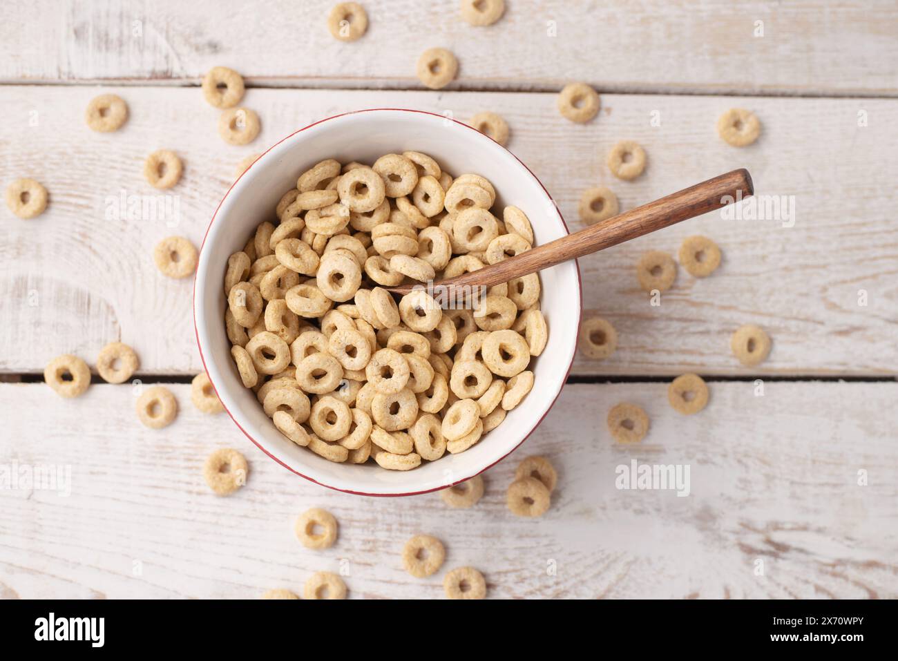 anneaux de céréales sains sur un fond de bois clair dans une assiette et dispersés sur la table. mangez le matin. Petit déjeuner sain pour enfants. Muesli sec Banque D'Images