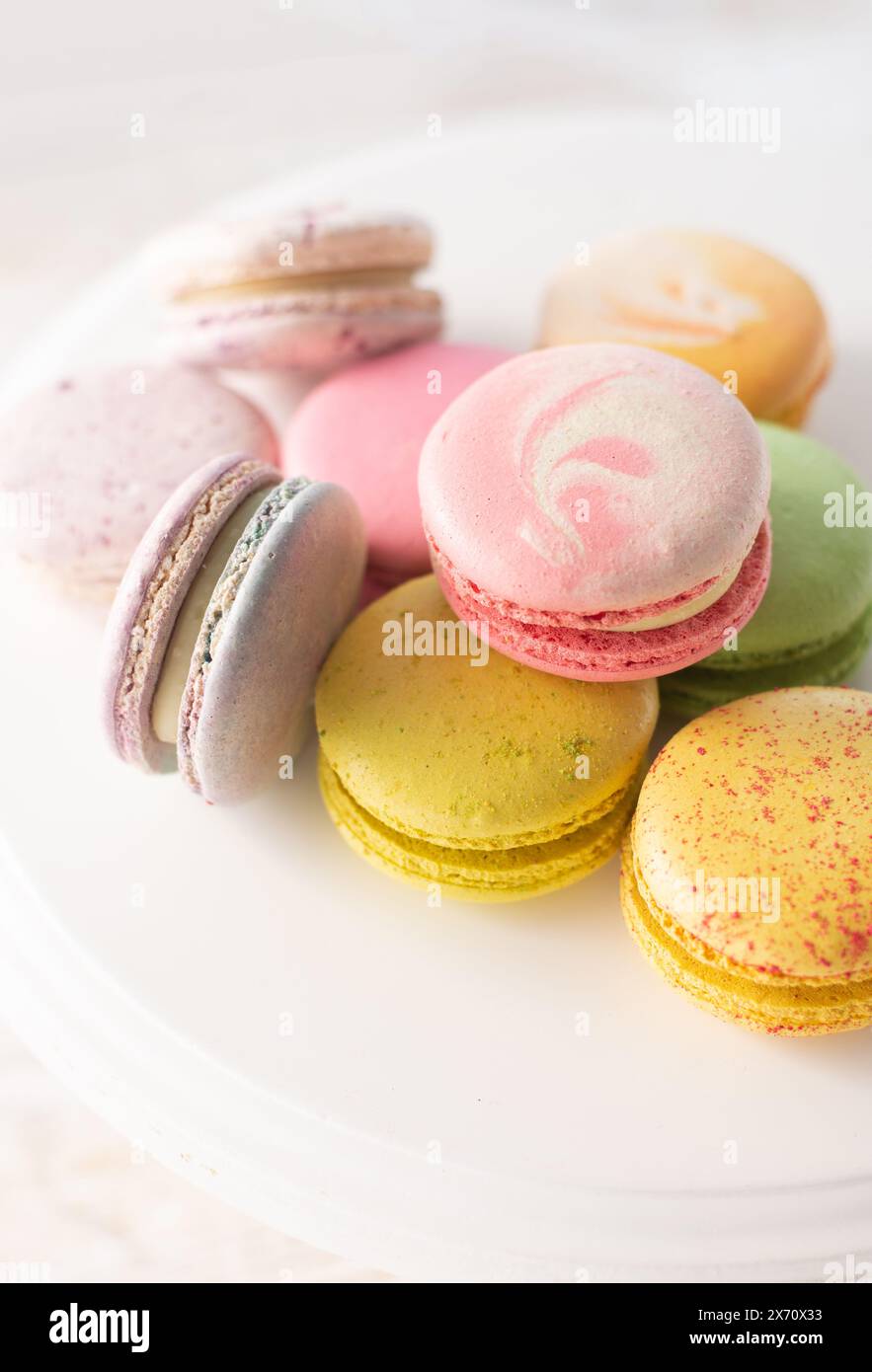 Macarons multicolores sur fond de bois avec des lumières douces et des ombres. Macarons doux sur table sur fond clair. Banque D'Images