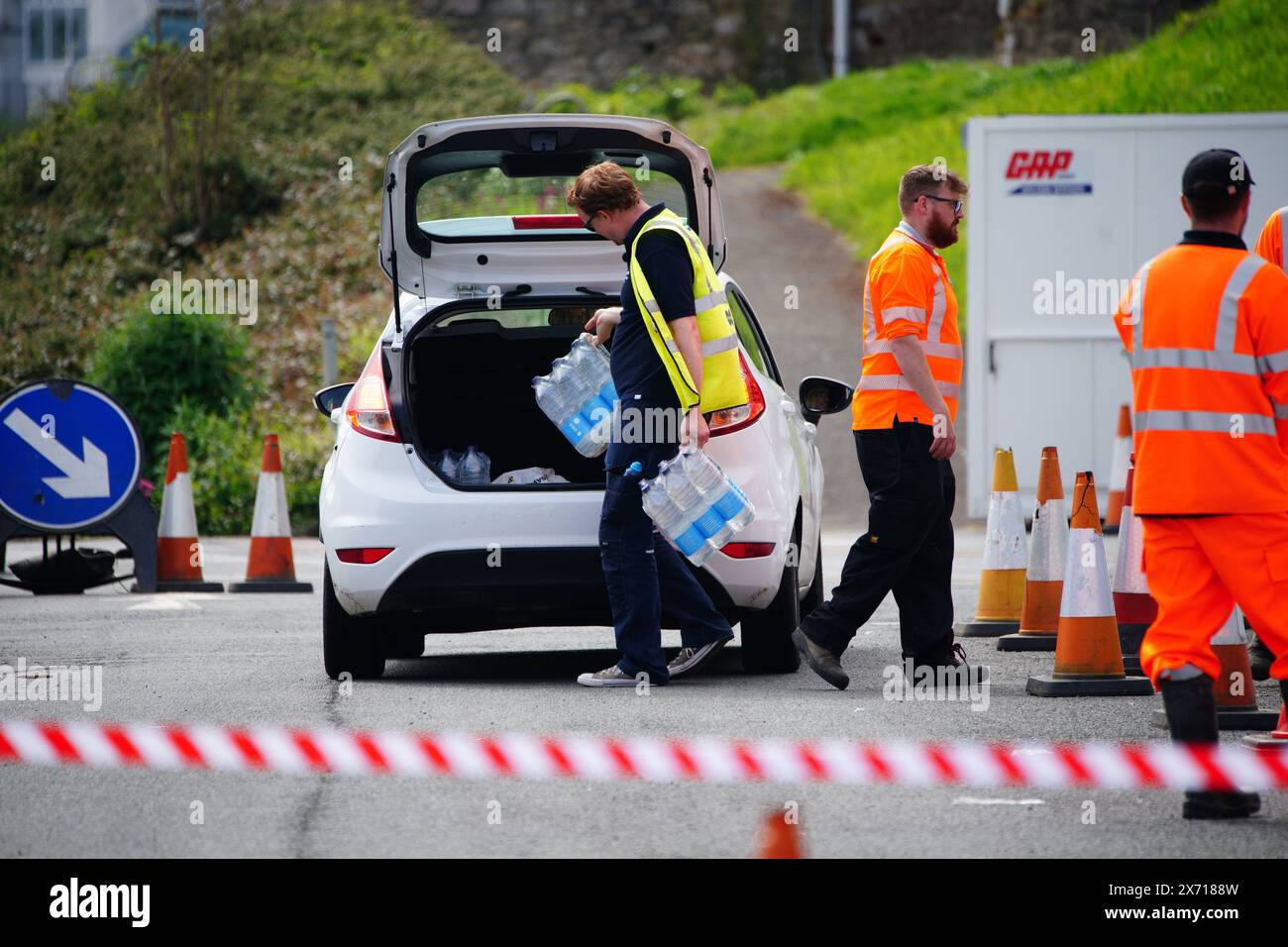 Les gens ramassent de l'eau en bouteille au parking Freshwater à Brixham. Environ 16 000 ménages et entreprises de la région de Brixham, dans le Devon, ont été priés de ne pas utiliser leur eau du robinet pour boire sans la faire bouillir et la refroidir d’abord, suite à la découverte de petites traces d’un parasite dans le réseau d’eau local. Date de la photo : vendredi 17 mai 2024. Banque D'Images