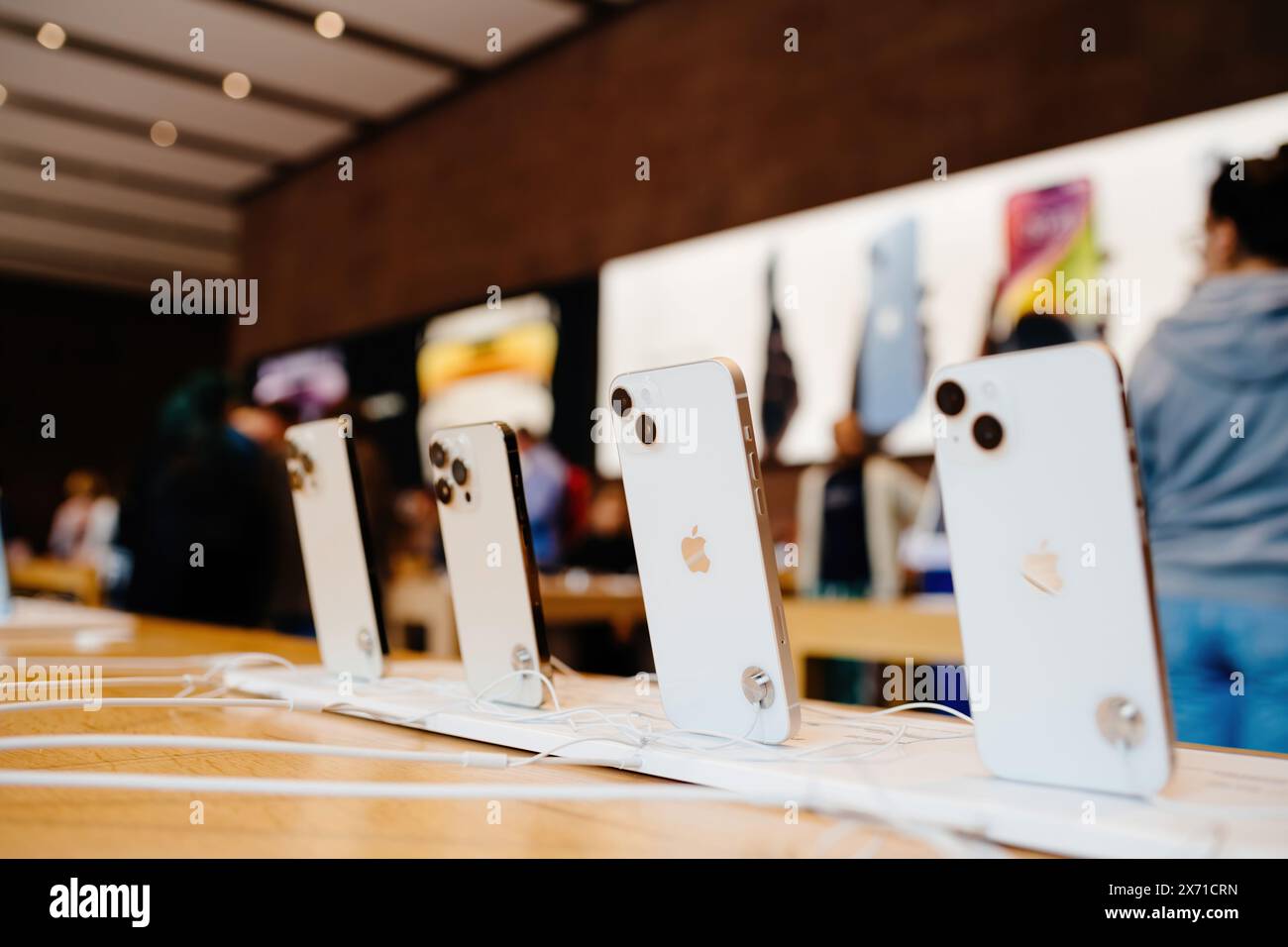 Paris, France - 28 octobre 2024 : une rangée des derniers ordinateurs et iPhones Apple est exposée dans un Apple Store, avec des silhouettes de personnes en arrière-plan, soulignant le design élégant et la technologie de pointe. Banque D'Images