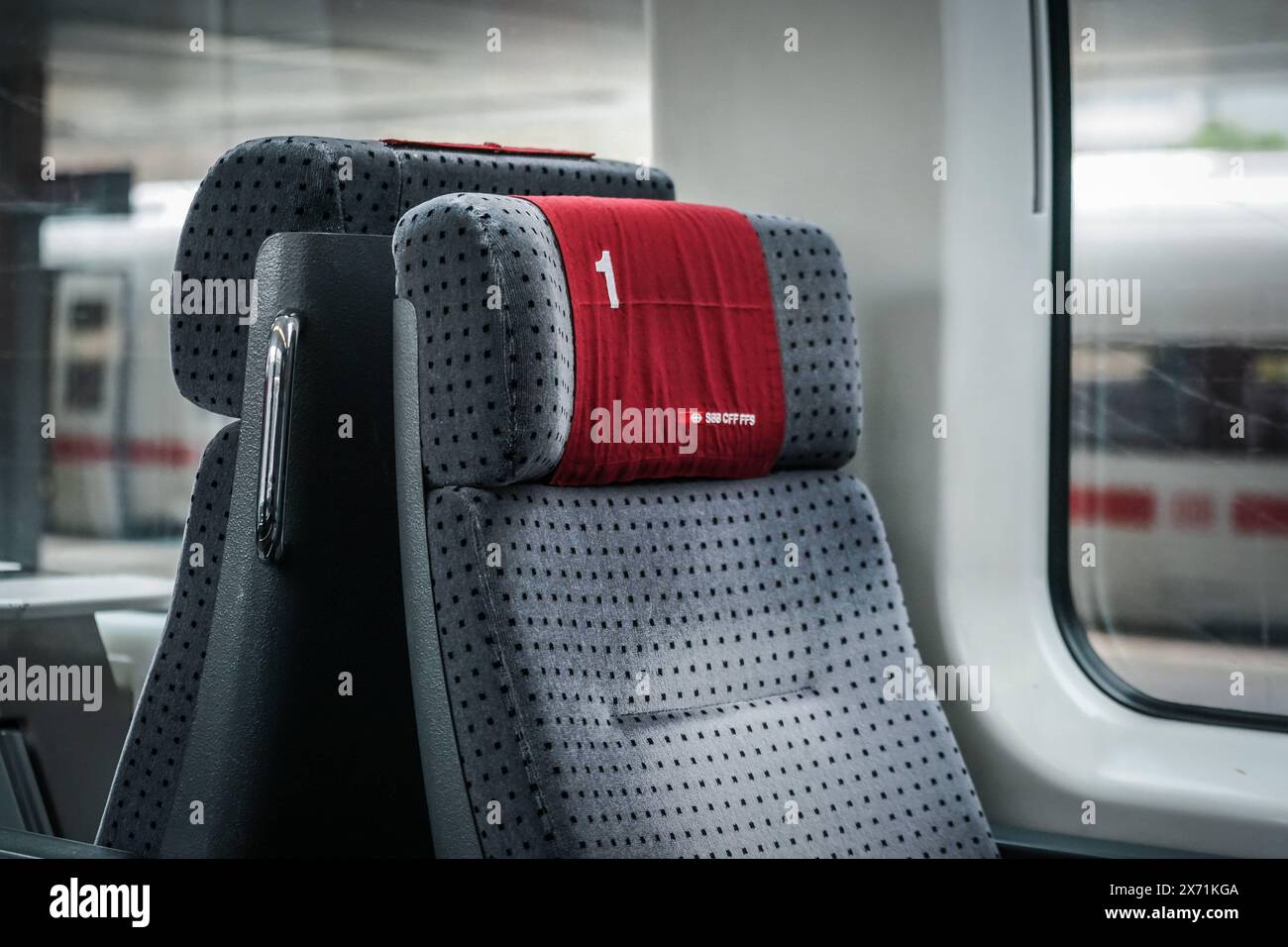 Symbolbild : Sitzplatz, erste Klasse, Zug, Schweizerische Bundesbahnen, SBB, Kopfstütze, Rote Abdeckung, Nummer 1, SBB-logo, SBB CFF FFS, Initialen, Deutsch, Französisch, Italienisch, gepolstert, grau, Muster, Punkte, Hintergrund, weitere Sitzplätze, erste Klasse, Komfort, Luxus, Reisen, Zugfahrt, Schweiz, Bahngesellschaft, hochwertig, Fahrgast, Sitzkomfort, Schienenverkehr, interieur, Premiumklasse, Reisekultur, Passagiere, Fernverkehr, Inlandsverkehr, internationales Reisen. *** Image symbolique Siège, première classe, train, chemins de fer fédéraux suisses, CFF, appuie-tête, couvercle rouge, numéro 1, logo SBB, SBB Banque D'Images