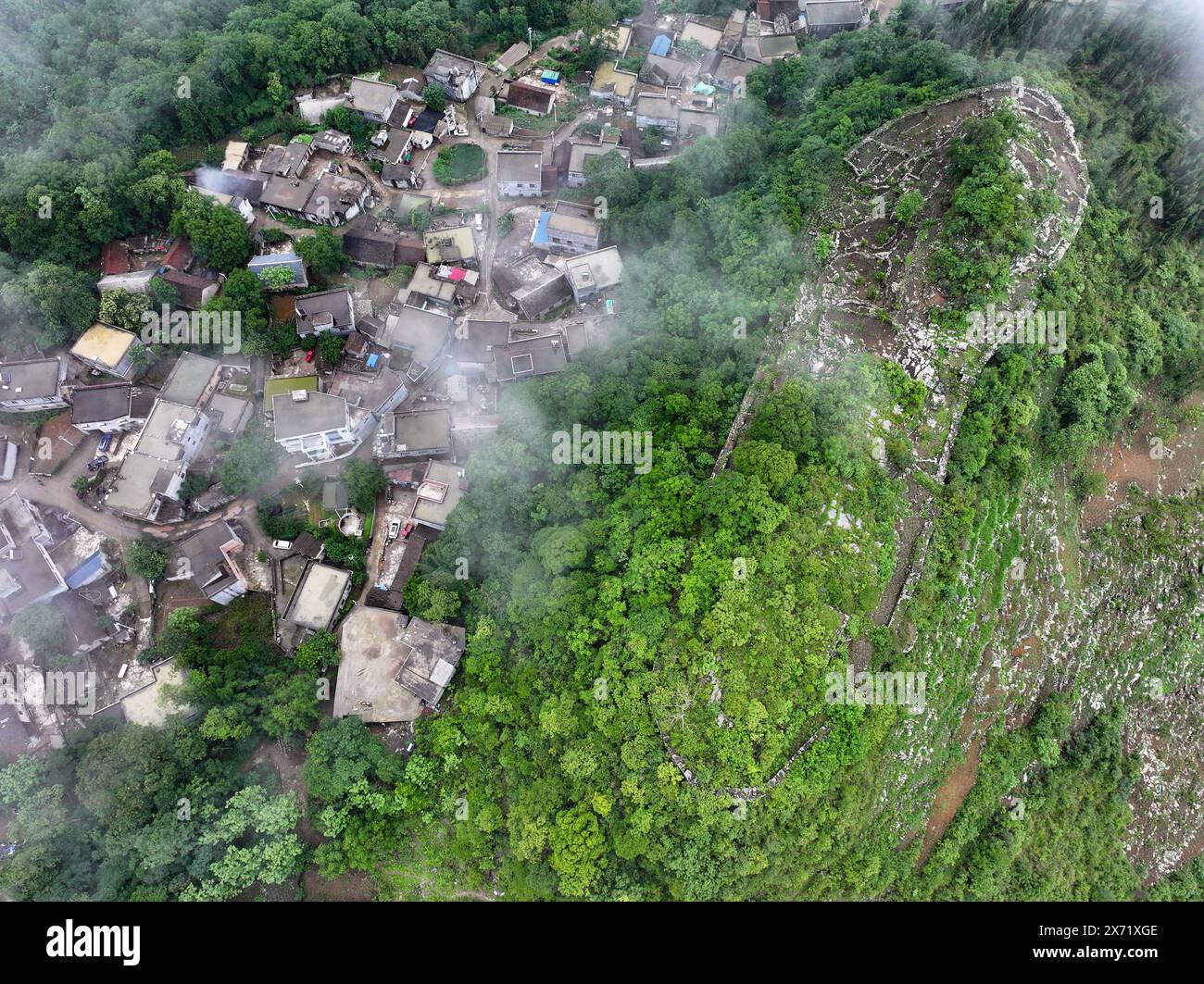 Qianxinan. 17 mai 2024. Une photo prise par un drone aérien le 17 mai 2024 montre une vue des ruines d'une ancienne ville datant de la dynastie Ming (1368-1644) au village de Pingzhai de la préfecture autonome de Bouyei-Miao de Qianxinan, dans la province du Guizhou au sud-ouest de la Chine. Le site apparaît de forme ovale vu d'en haut, couvrant une superficie d'environ 18 000 mètres carrés, avec plus de 900 mètres de murs de pierre restés. Crédit : Liu Xu/Xinhua/Alamy Live News Banque D'Images
